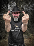 A bearded man wearing a black hat and a black graphic t-shirt with the text 'MY PRONOUND WITCH / WITCH Y' on the front, holding up his middle fingers against a dark, wooded outdoor background.